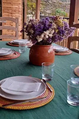 a table with plates and a vase filled with flowers at Piso con preciosas vistas, patio privado y amplio garaje in Puentedeume