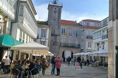 a group of people walking down a street with a clock tower at Piso con preciosas vistas, patio privado y amplio garaje in Puentedeume