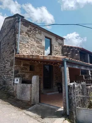 an outside view of a stone house with a wooden porch at La Gavina in Beáriz