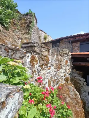 a kitchen with a table and stools in front of a stone wall at Casa Yañez in Chantada