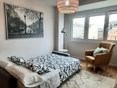 a bedroom with a bed and a chair and windows at Adarve, con parking y vistas a la muralla in Lugo