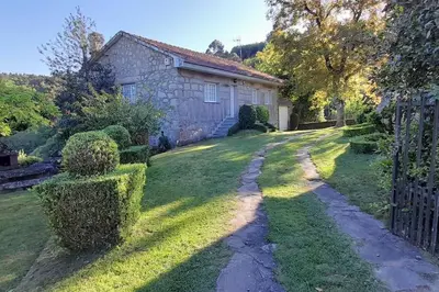 a stone house with a gate in a yard at Casa rural con piscina en la Ribeira Sacra. in Campos