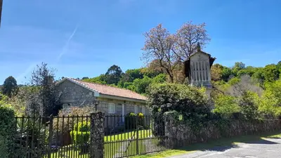 an old house with a fence and a church at Casa rural con piscina en la Ribeira Sacra. in Campos