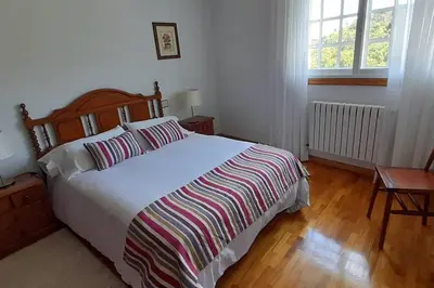a bedroom with a large bed with a striped blanket at Casa rural con piscina en la Ribeira Sacra. in Campos