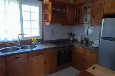 a kitchen with wooden cabinets and a sink and a window at Casa rural con piscina en la Ribeira Sacra. in Campos