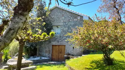 a stone house with a wooden door in a yard at Casa rural con piscina en la Ribeira Sacra. in Campos
