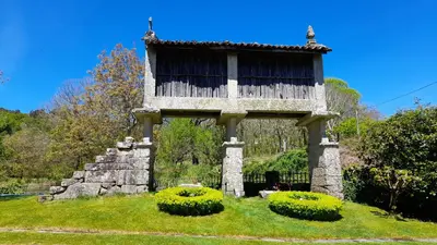 an old building on top of a lush green field at Casa rural con piscina en la Ribeira Sacra. in Campos