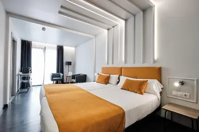 a bedroom with a large white bed with an orange blanket at Hotel Lux Santiago in Santiago de Compostela