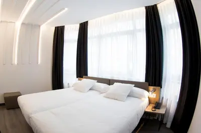 a bedroom with a white bed with a large window at Hotel Lux Santiago in Santiago de Compostela