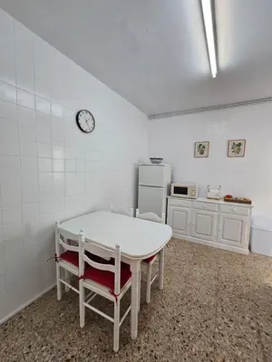 a kitchen with a white table and a clock on the wall at MEDA Padrón in Padrón