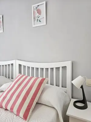 a white bedroom with a bed with a striped pillow at MEDA Padrón in Padrón