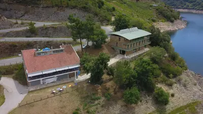 a house on top of a hill next to a river at COMPLEXO TURISTICO PONTE MOURULLE in Insúa