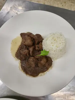 a plate of food with meat and rice on a table at COMPLEXO TURISTICO PONTE MOURULLE in Insúa