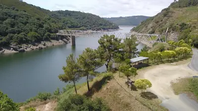 a bridge over a river next to a mountain at COMPLEXO TURISTICO PONTE MOURULLE in Insúa