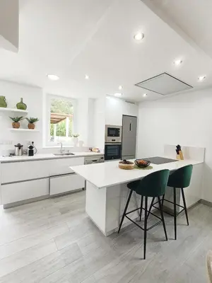 a white kitchen with a counter and two chairs at Casa da Americana II in Boqueijón