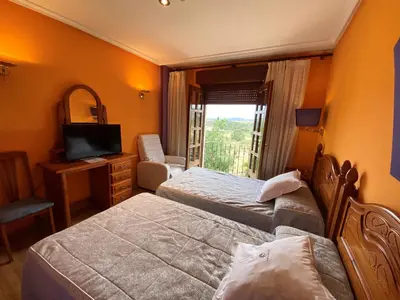 a hotel room with two beds and a television at Tierra De Lobos in Puebla de Sanabria