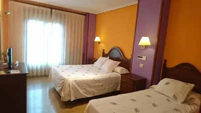 a hotel room with two beds and a television at Tierra De Lobos in Puebla de Sanabria