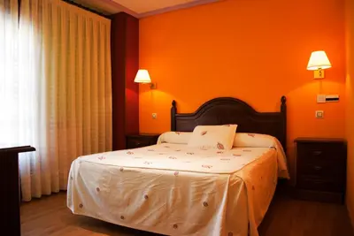 a bedroom with orange walls and a bed with white sheets at Tierra De Lobos in Puebla de Sanabria