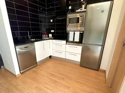 a kitchen with stainless steel appliances and black tiled walls at Arnela Reinante in Barreiros