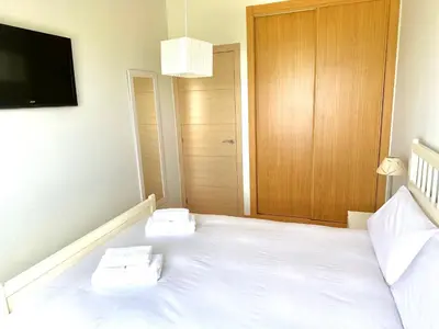 a bedroom with a large white bed and a television at Arnela Reinante in Barreiros