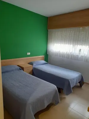 a room with two beds and a green wall at Micampus Lugo Student Residence in Lugo