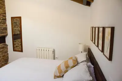 a bedroom with a white bed and a radiator at Casa de las Flores / Casa de campo LUGO in A Pontenova