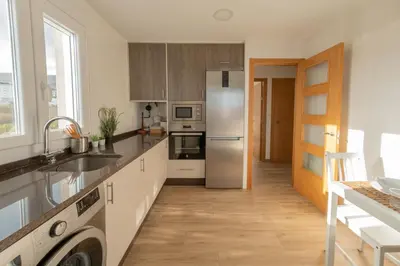 a kitchen with stainless steel appliances and wooden floors at Piso en el puerto con vistas al Mar+Wifi+ SmartTv in Burela de Cabo