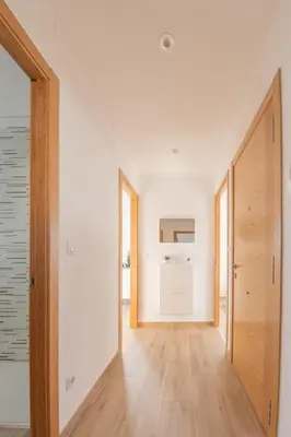 a hallway with white walls and a wooden door at Piso en el puerto con vistas al Mar+Wifi+ SmartTv in Burela de Cabo