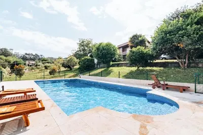 a swimming pool with two wooden benches next to it at Casa Rústica O Abeiro in Pontevedra