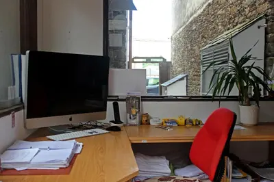 a desk with a computer monitor and a red chair at Albergue San Lázaro in Sarria