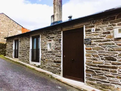 a stone building with a brown door on a street at Albergue San Lázaro in Sarria