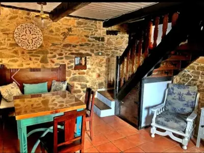 a living room with a table and a stone wall at Casa do Duende in Tedejo
