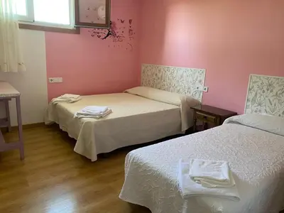 two beds in a room with pink walls and wooden floors at Casa da Pinguela Camino Inglés in Ordes