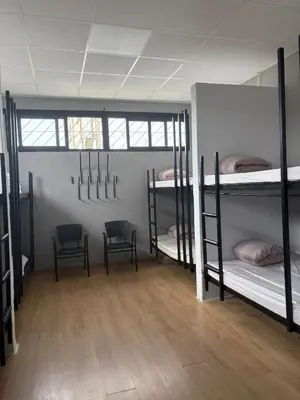a room with three bunk beds and two chairs at Hostel Azul Cielo in O Pedrouzo