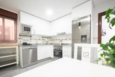 a kitchen with white cabinets and a stainless steel refrigerator at Apartamento Las Candelas, Ares in Ares