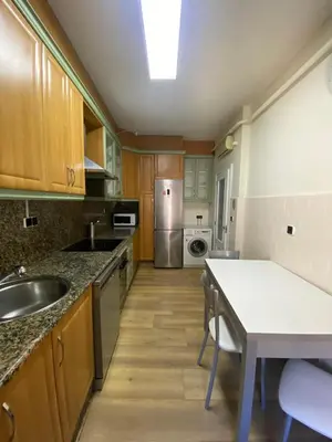 a kitchen with wooden cabinets and a sink and a table at PISO EN ESTACION DE MONFORTE DE LEMOS in Monforte de Lemos