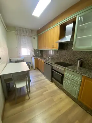 a kitchen with wooden cabinets and a table and a counter at PISO EN ESTACION DE MONFORTE DE LEMOS in Monforte de Lemos