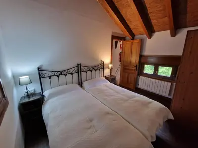 a bedroom with a large bed with white sheets at El Descanso de Sanabria in Trefacio