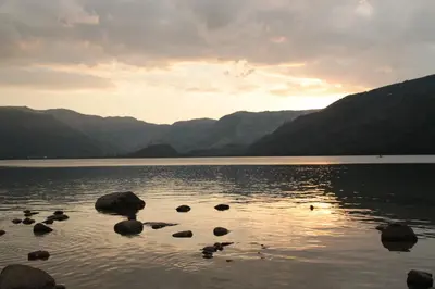 a group of rocks in the water with mountains at El Descanso de Sanabria in Trefacio