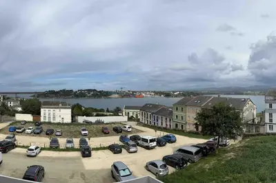 a parking lot with cars parked next to a body of water at Apartamento Cantabrico vistas a la Ría deRibadeo in Ribadeo