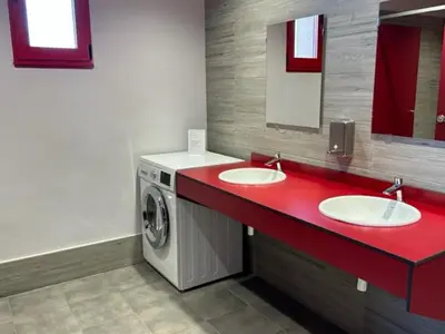 a bathroom with two sinks and a washing machine at ALBERGUE A POBRA DO BROLLON in Puebla del Brollón
