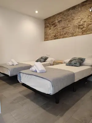 three beds in a room with a brick wall at Pensión SP 55 by Bossh! Hotels in Santiago de Compostela
