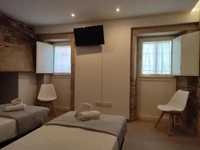 a bedroom with two beds and a tv on the wall at Pensión SP 55 by Bossh! Hotels in Santiago de Compostela