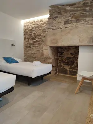 a room with two beds and a stone fireplace at Pensión SP 55 by Bossh! Hotels in Santiago de Compostela