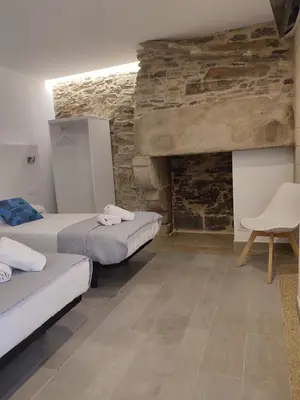 a room with two beds and a stone wall at Pensión SP 55 by Bossh! Hotels in Santiago de Compostela