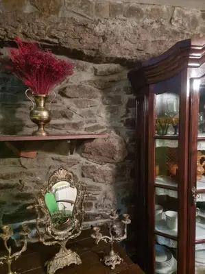 a room with a mirror and a stone wall at Casa Rural Maria de Isidro in Caboalles de Arriba