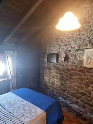 a bedroom with a bed and a stone wall at Casa Rural Maria de Isidro in Caboalles de Arriba