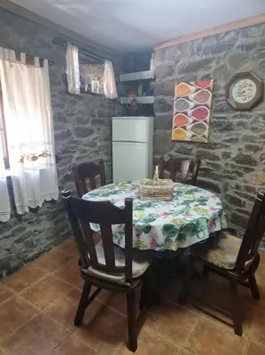a dining room with a table and chairs and a stone wall at Casa Rural Maria de Isidro in Caboalles de Arriba