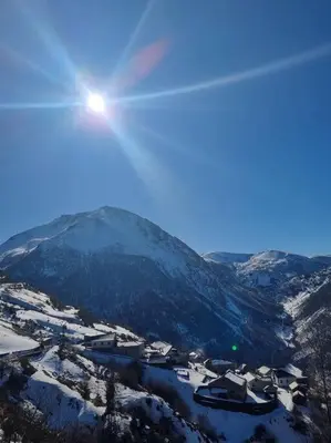 a view of a snowy mountain with the sun in the sky at Casa Rural Maria de Isidro in Caboalles de Arriba
