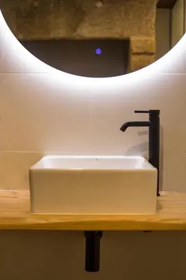 a white sink on a wooden counter with a mirror at hostal Nomade Santiago in Santiago de Compostela